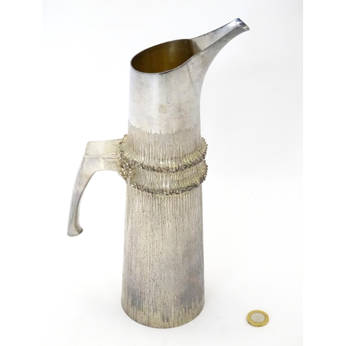 269 - Christopher Nigel Lawrence : An Elizabeth II Modernist silver ewer / pitcher / jug with textured bod... 
