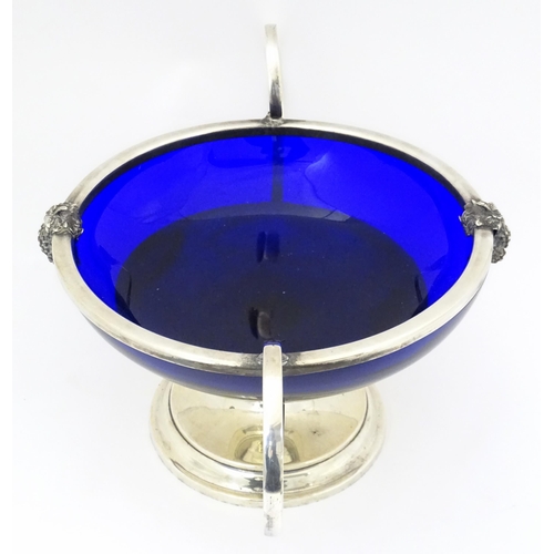 534 - A silver plate pedestal bowl with twin handles and fruiting vine decoration, with blue glass liner. ... 