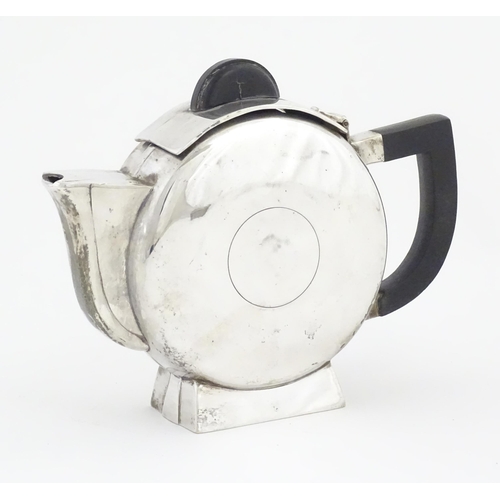 962 - An Art Deco silver plate teapot with ebonised handle and finial, the body with circular detail, in t... 