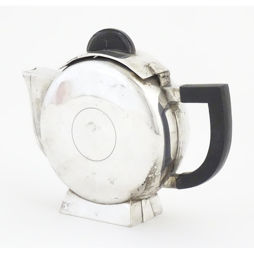 962 - An Art Deco silver plate teapot with ebonised handle and finial, the body with circular detail, in t... 