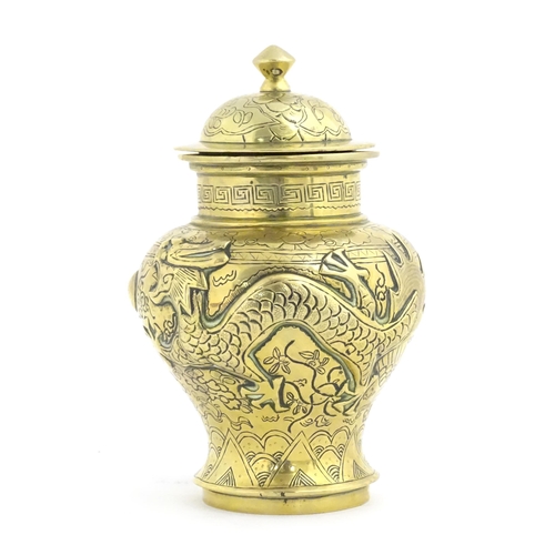 992 - A Chinese cast brass vase and cover of baluster form with relief decoration depicting dragons and a ... 