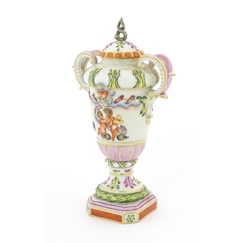 64A - A Capodimonte twin handled vase and cover with hand painted cherub / putti, mask and foliate decorat... 