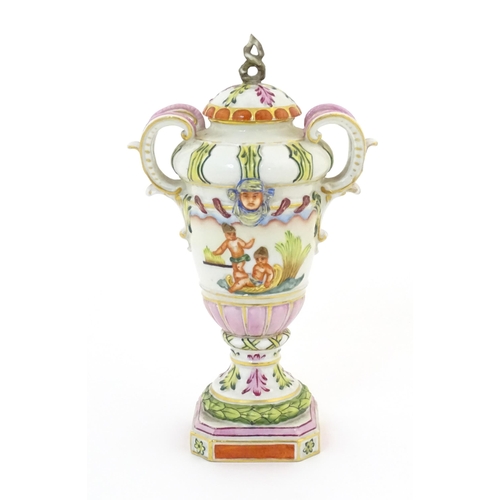 64A - A Capodimonte twin handled vase and cover with hand painted cherub / putti, mask and foliate decorat... 