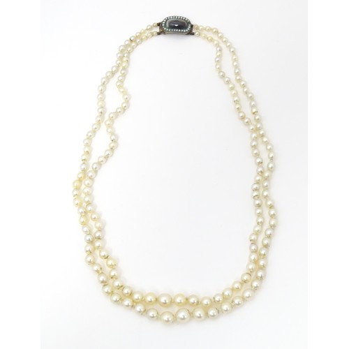 730 - A two strand graduated pearl necklace with yellow metal clasp set with agate and seed pearls. Approx... 