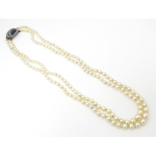 730 - A two strand graduated pearl necklace with yellow metal clasp set with agate and seed pearls. Approx... 