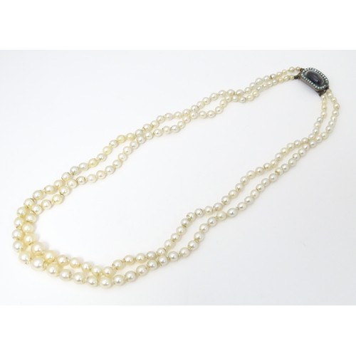 730 - A two strand graduated pearl necklace with yellow metal clasp set with agate and seed pearls. Approx... 