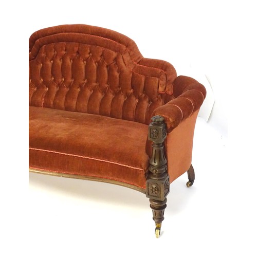 1453 - A 19thC mahogany sofa with deep buttoned upholstery and a carved frame, having gadrooned finials and... 