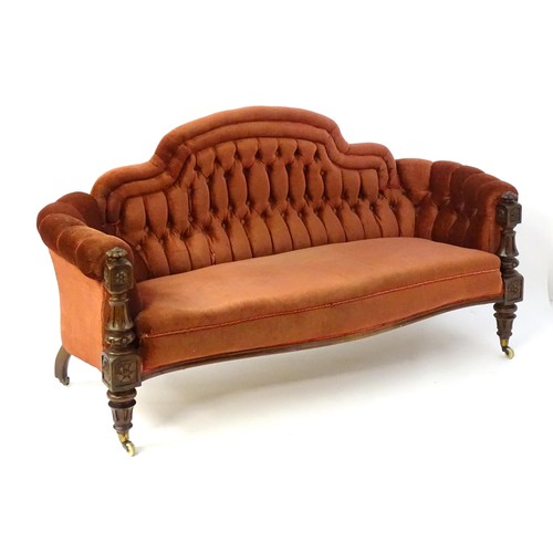 1453 - A 19thC mahogany sofa with deep buttoned upholstery and a carved frame, having gadrooned finials and... 