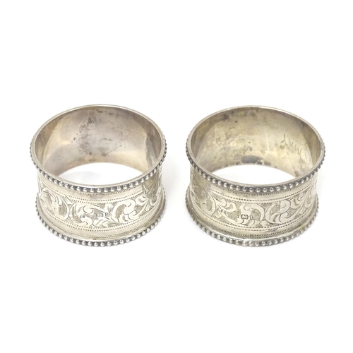 384 - A pair of silver napkin rings with engraved acanthus scrolls decoration, hallmarked Birmingham 1911,... 