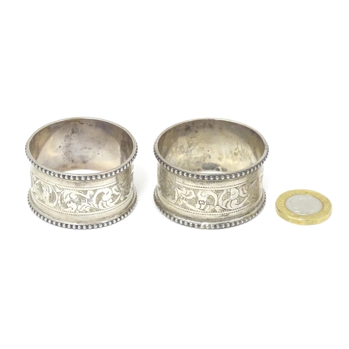 384 - A pair of silver napkin rings with engraved acanthus scrolls decoration, hallmarked Birmingham 1911,... 