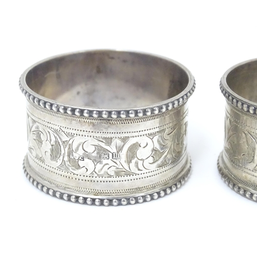 384 - A pair of silver napkin rings with engraved acanthus scrolls decoration, hallmarked Birmingham 1911,... 