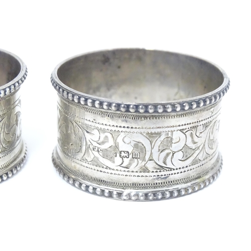 384 - A pair of silver napkin rings with engraved acanthus scrolls decoration, hallmarked Birmingham 1911,... 