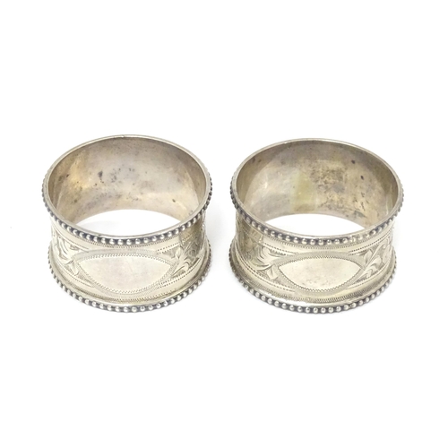 384 - A pair of silver napkin rings with engraved acanthus scrolls decoration, hallmarked Birmingham 1911,... 