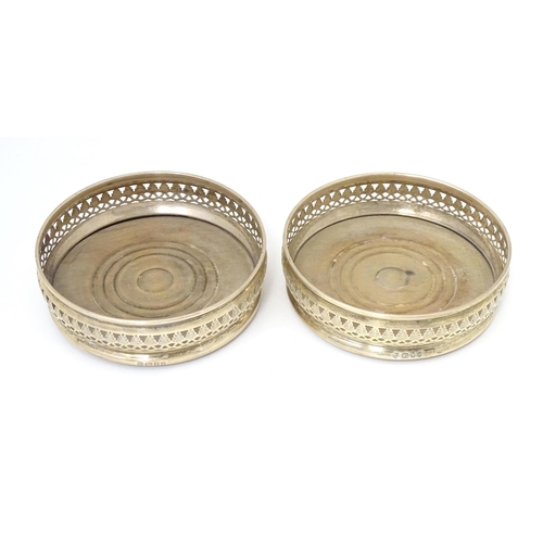 385 - A pair of silver bottle coasters with turned wooden bases, hallmarked London 1968. Approx. 5 1/4