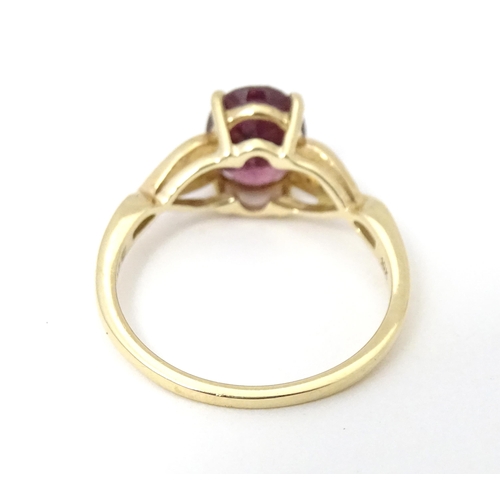 567 - A 9ct gold set with central Mahenge garnet flanked by white zircon. Ring size approx. N