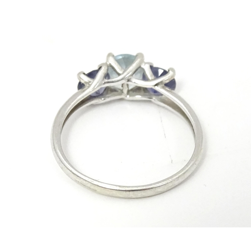 568 - A 9ct white gold ring set with central aquamarine flanked by iolite. Ring size approx. O 1/2