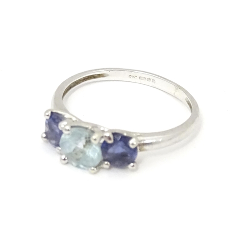 568 - A 9ct white gold ring set with central aquamarine flanked by iolite. Ring size approx. O 1/2