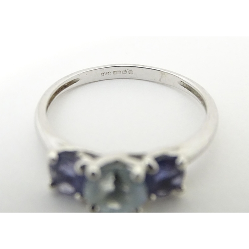 568 - A 9ct white gold ring set with central aquamarine flanked by iolite. Ring size approx. O 1/2