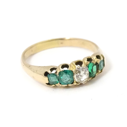 619 - An 18ct gold ring set with central diamond flanked by two emeralds. Together with insurance valuatio... 