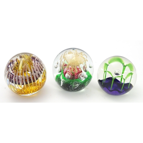 176 - Three assorted paperweights to include an example by Langham glass designed by Paul Miller, together... 