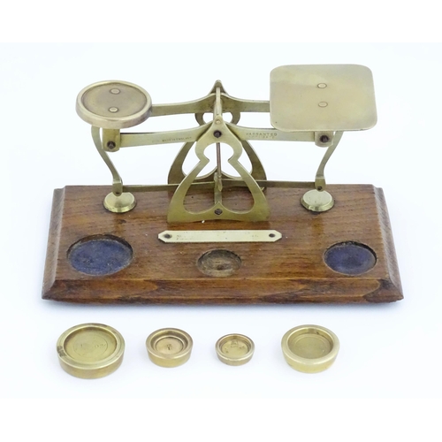 1082 - Victorian brass postal scales on a wooden base. Together with four graduated brass weights. Scales a... 