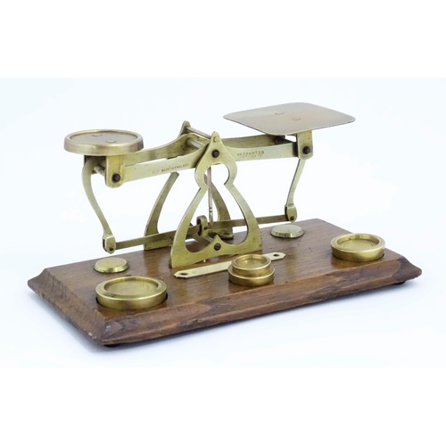 1082 - Victorian brass postal scales on a wooden base. Together with four graduated brass weights. Scales a... 