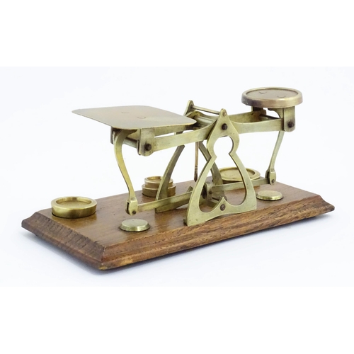 1082 - Victorian brass postal scales on a wooden base. Together with four graduated brass weights. Scales a... 