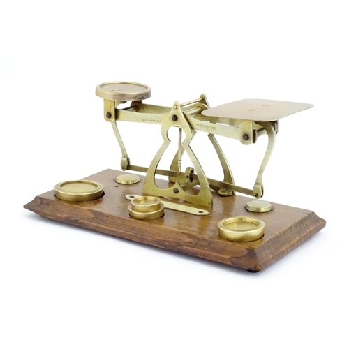 1082 - Victorian brass postal scales on a wooden base. Together with four graduated brass weights. Scales a... 