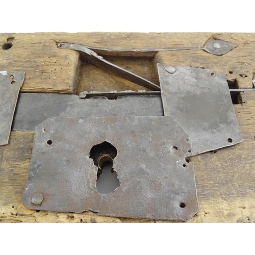 1084 - An old door lock mechanism and key mounted to a wooden panel. Panel approx. 7