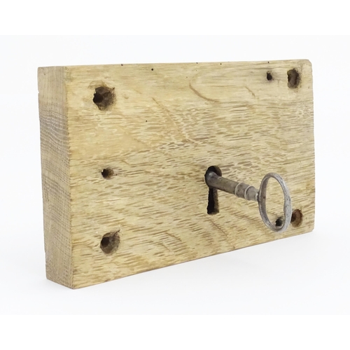 1085 - An old door lock mechanism and key mounted to an oak panel. Panel approx. 5 1/2