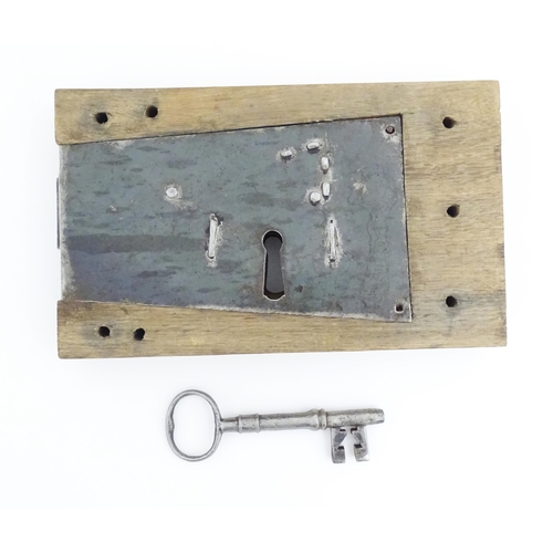 1085 - An old door lock mechanism and key mounted to an oak panel. Panel approx. 5 1/2