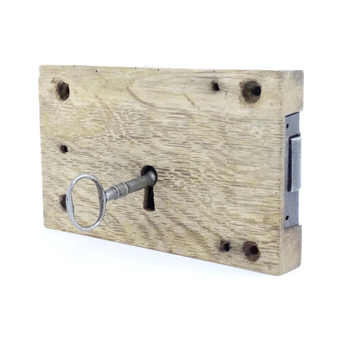 1085 - An old door lock mechanism and key mounted to an oak panel. Panel approx. 5 1/2