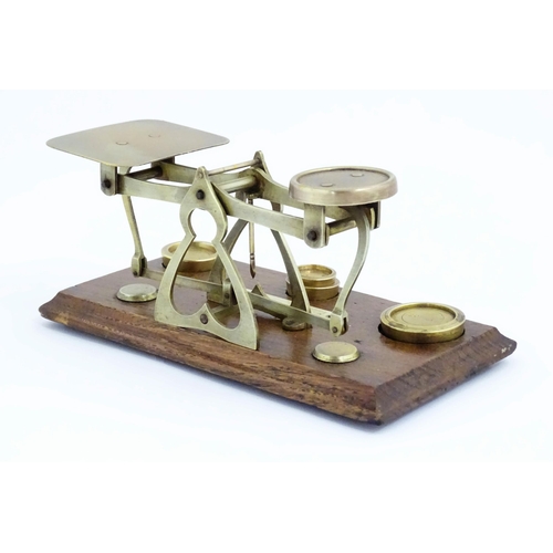 1082 - Victorian brass postal scales on a wooden base. Together with four graduated brass weights. Scales a... 