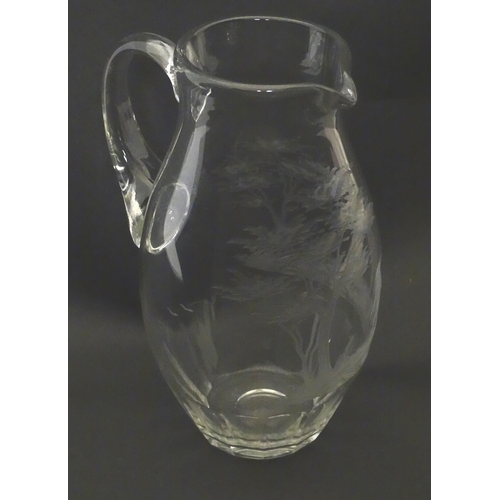 203 - A glass jug with loop handle decorated with etched Alpine Ibex in landscape. Approx 10