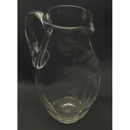 203 - A glass jug with loop handle decorated with etched Alpine Ibex in landscape. Approx 10