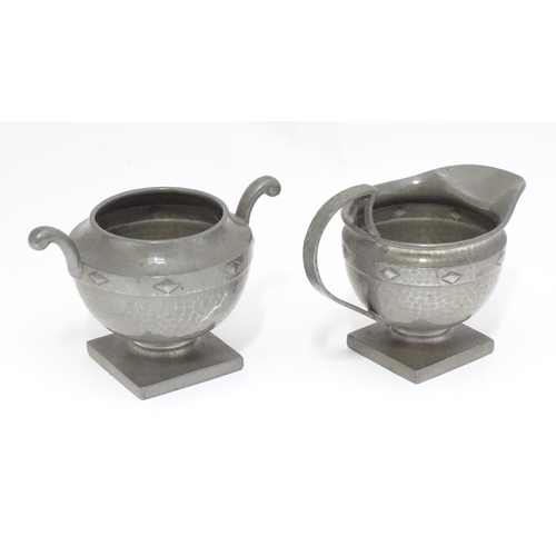 34 - A pewter pedestal cream jug and sugar bowl with hammered and banded decoration. Stamped under Don Pe... 