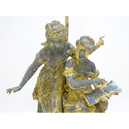 73 - A mid 20thC table lamp, of metal construction and decorated with two singing maidens standing on a s... 