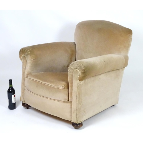 116 - A mid 20thC Howard style armchair with scrolled arms and raised on squat bun front feet and squared ... 