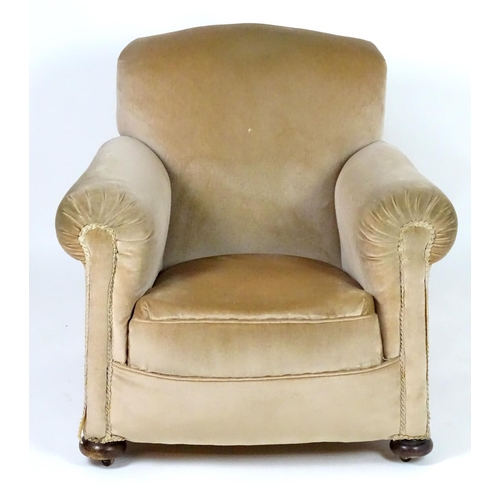 116 - A mid 20thC Howard style armchair with scrolled arms and raised on squat bun front feet and squared ... 