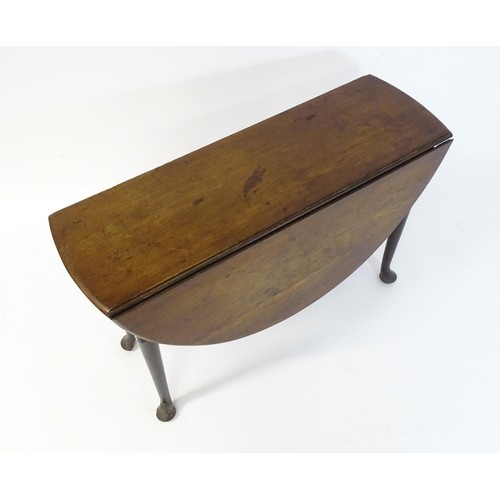 65 - A late Georgian mahogany drop flap table, the table having two demi lune leaves and raised on turned... 