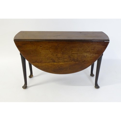 65 - A late Georgian mahogany drop flap table, the table having two demi lune leaves and raised on turned... 