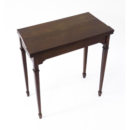 77 - A late 19thC / early 20thC mahogany card table with satinwood inlay, a crossbanded top and tapering ... 