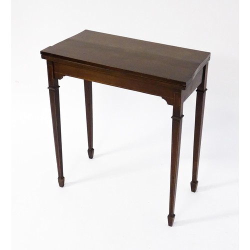 77 - A late 19thC / early 20thC mahogany card table with satinwood inlay, a crossbanded top and tapering ... 