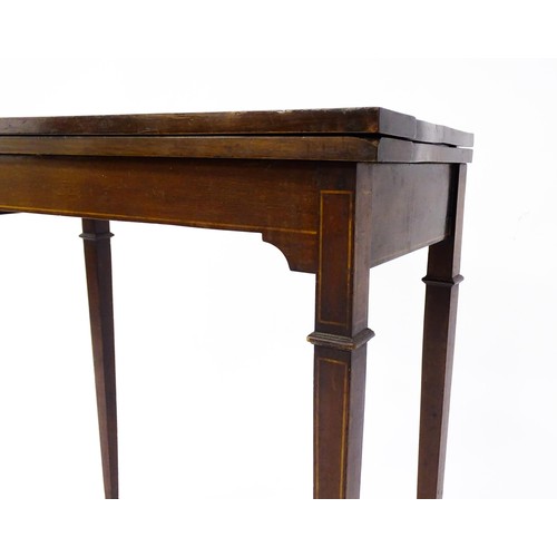 77 - A late 19thC / early 20thC mahogany card table with satinwood inlay, a crossbanded top and tapering ... 