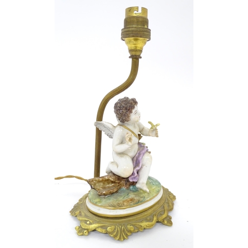 293 - A Continental gilt metal table lamp with ceramic figure depicting a cherub holding a bird. Bears old... 