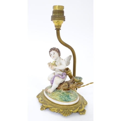 293 - A Continental gilt metal table lamp with ceramic figure depicting a cherub holding a bird. Bears old... 