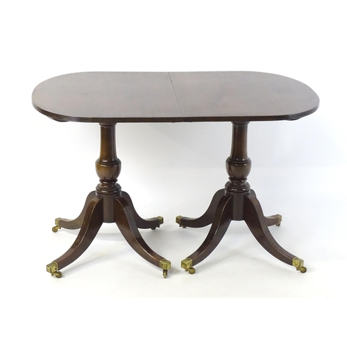 354 - A Regency style double pedestal mahogany dining table with a reeded edge and an additional leaf. Un-... 