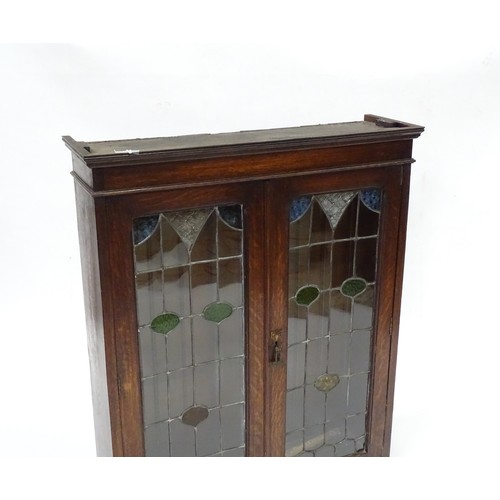 313 - An early 20thC oak cabinet with two leaded glass panelled doors. Approx 34