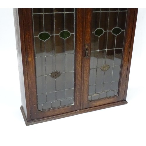 313 - An early 20thC oak cabinet with two leaded glass panelled doors. Approx 34