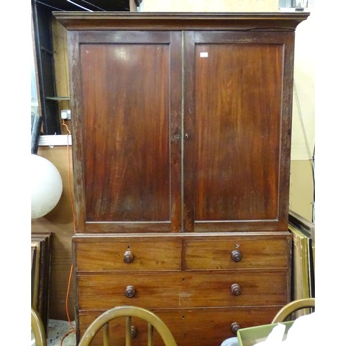 338 - An early 19thC mahogany linen press, having a moulded cornice above two panelled doors and the base ... 